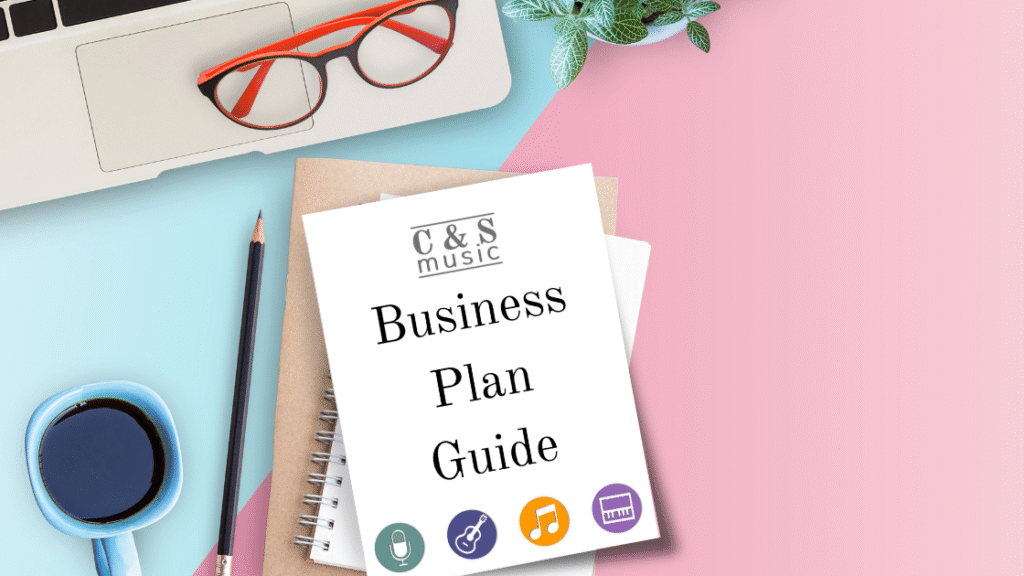the C&S musician business plan pdf workbook on top of a notebook on a desk with a pencil, computer, and glasses.