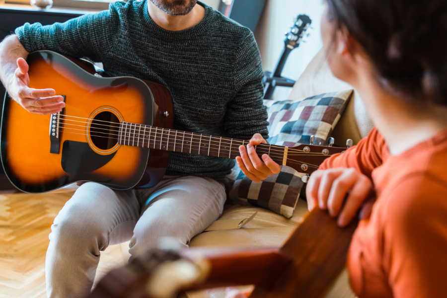 man and woman sitting on a couch with guitars while talking
