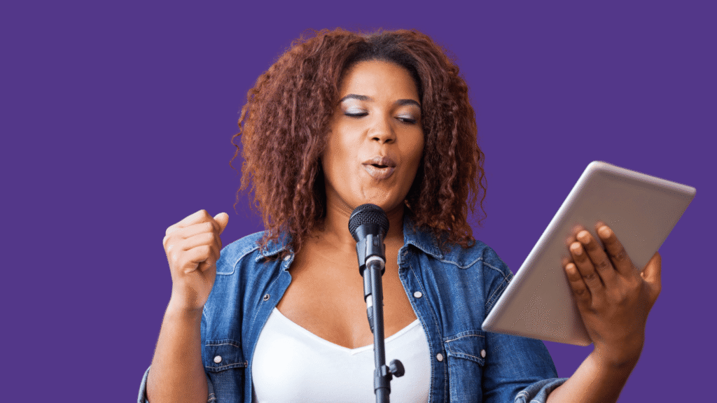 a woman in a jean jacket holding an iPad and doing her daily vocal routine into a microphone