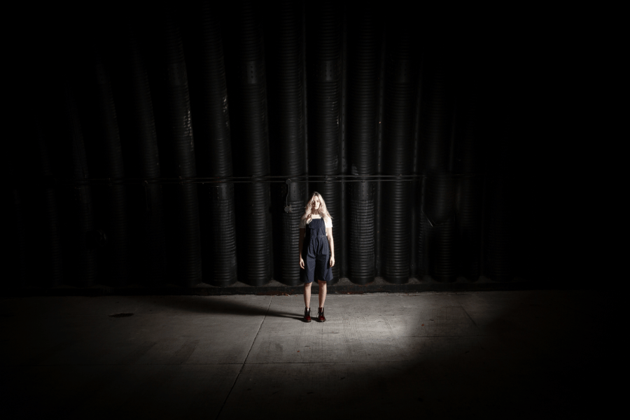 a woman standing alone in a spotlight in front of a black curtain