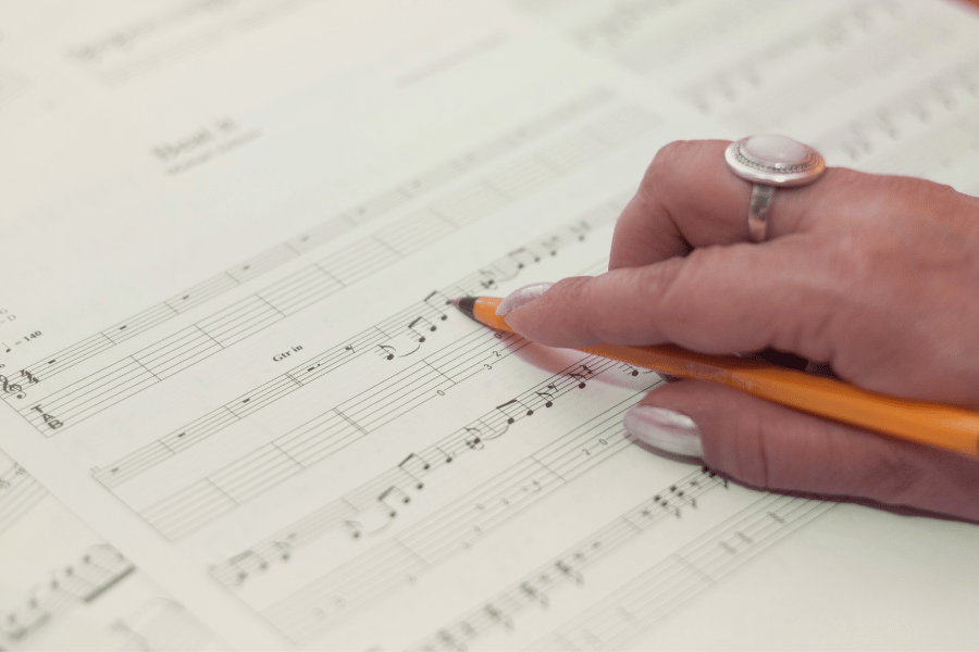 a hand with a ring on the finger holding a pencil, working on sight singing training in a private music lesson