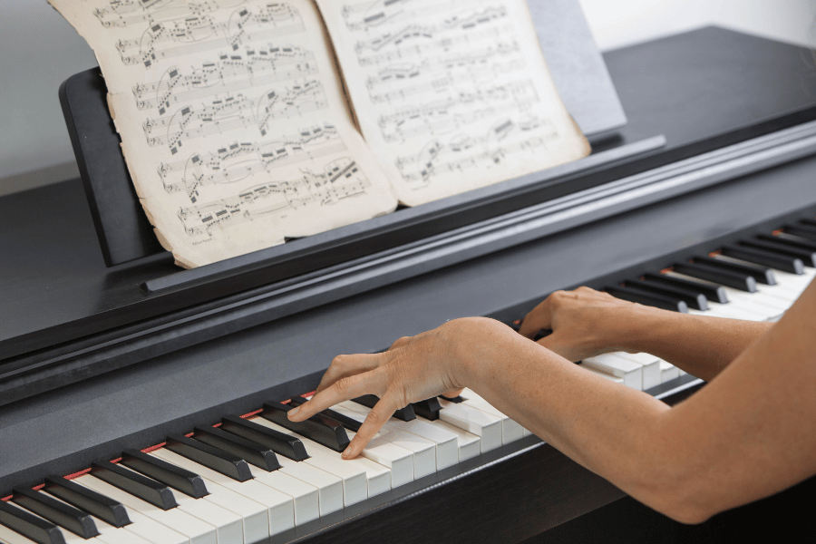 a pianist sitting at a piano with sheet music.